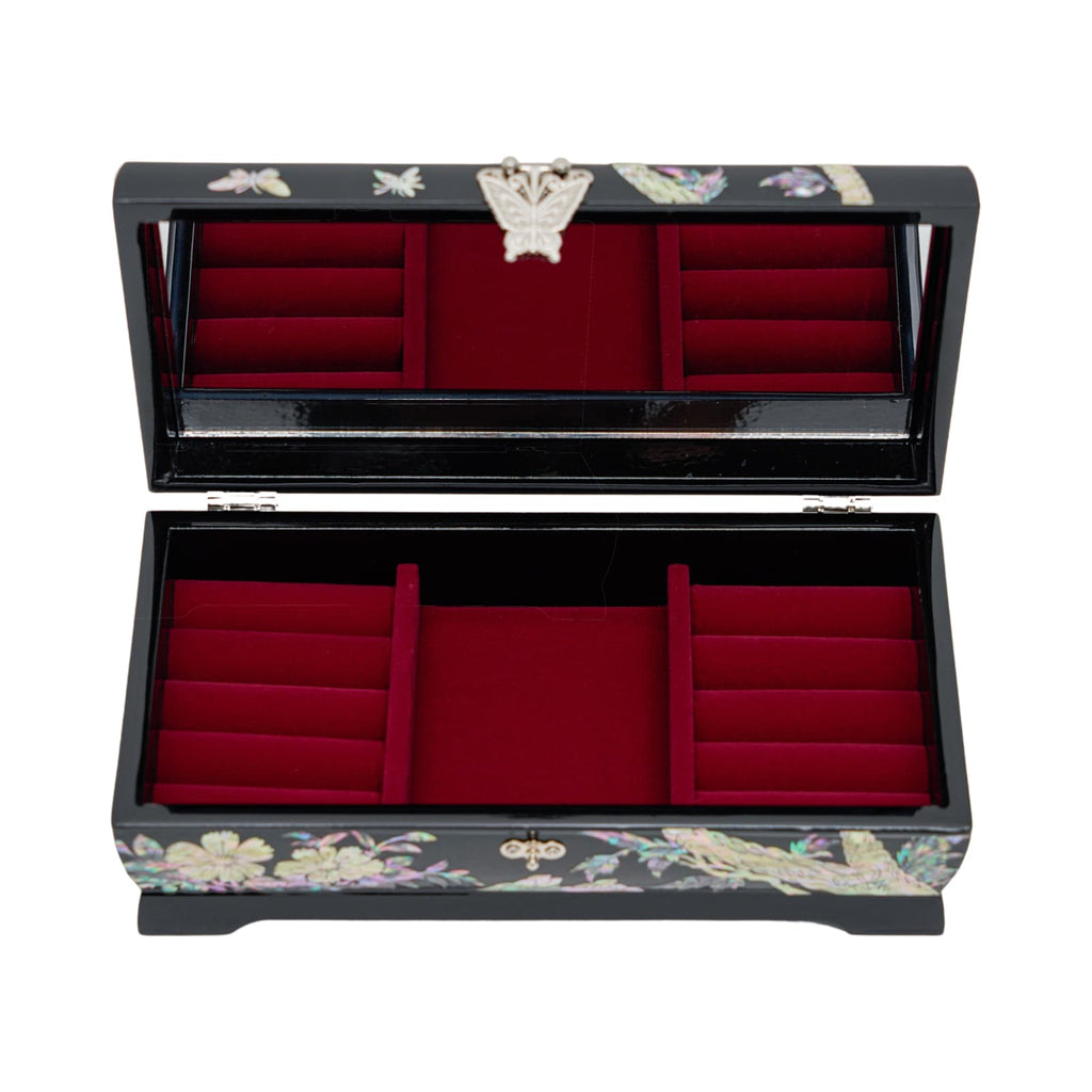 An open black jewelry box with red velvet lining and various compartments, featuring a mother-of-pearl inlay design with florals on the exterior.