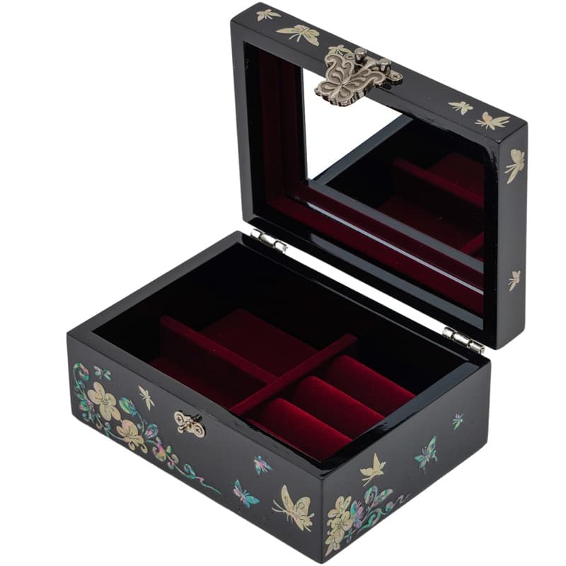 An open black lacquer box with mother-of-pearl inlays and a mirrored lid, revealing a red velvet-lined interior with compartments, reflecting traditional Asian elegance.