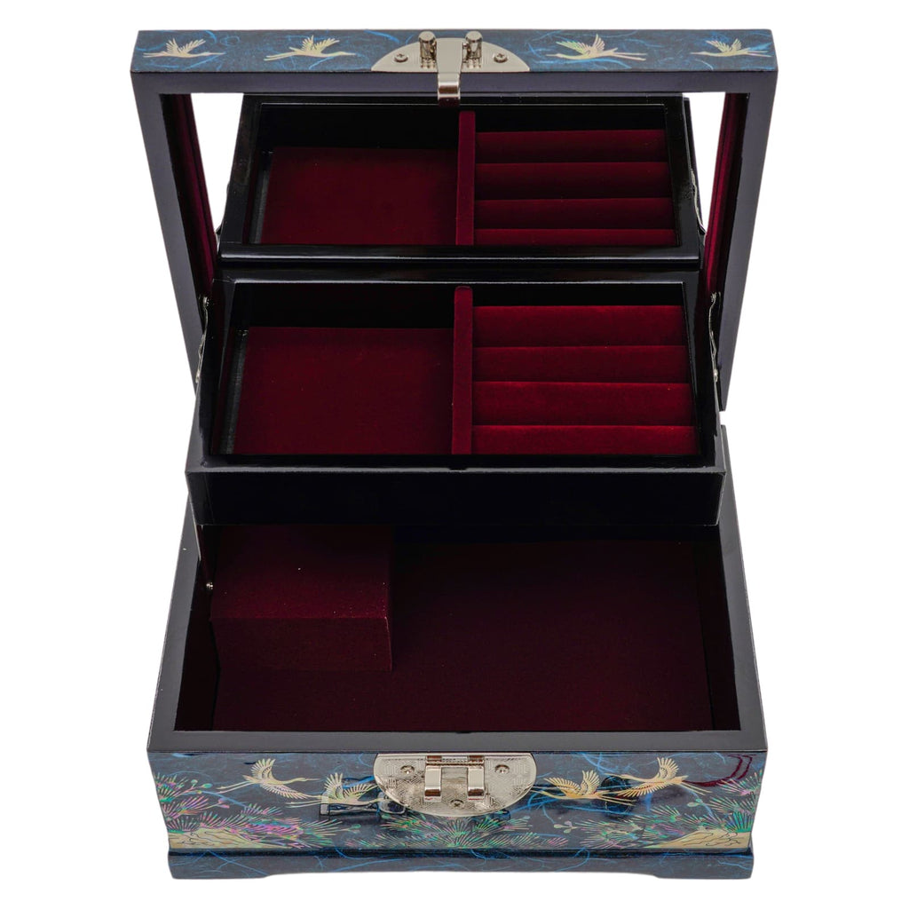 An open mother-of-pearl inlaid box with three layers of red velvet-lined compartments, featuring a dark exterior with crane and floral motifs and metallic hinges and latch.