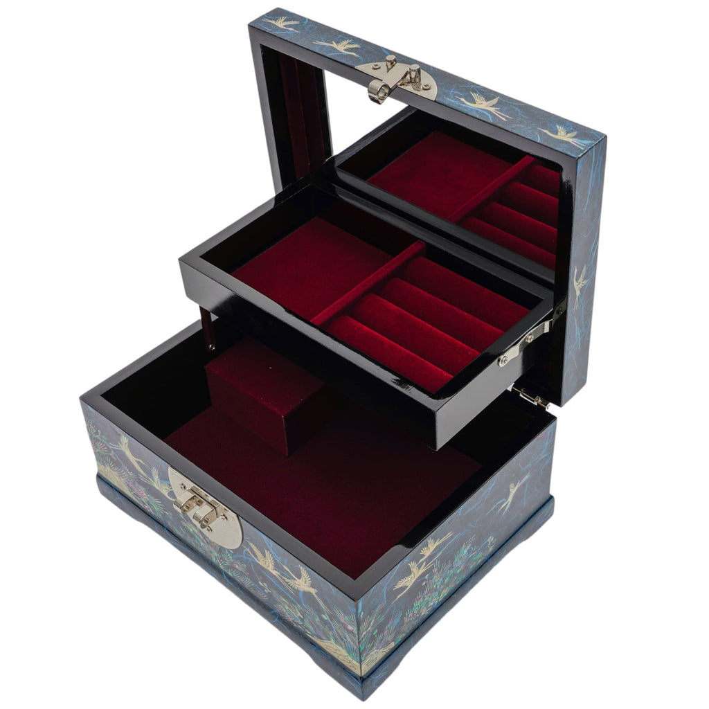 An open mother-of-pearl inlaid jewelry box with two drawers, red velvet interiors, metallic hinges, and a latch, adorned with a crane and floral design on a dark background.
