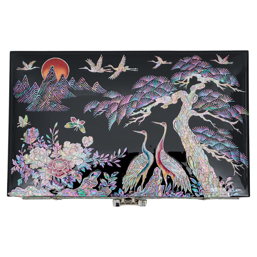  A rectangular black lacquer box with mother-of-pearl inlay depicting cranes and a pine tree against a stylized mountainous background with a rising sun, showing a fusion of vibrant colors and traditional Korean art.