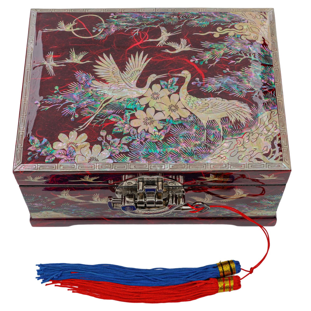 A red and multicolored Mother of Pearl box with crane and floral designs, secured with a metal clasp and adorned with a traditional Korean norigae tassel.