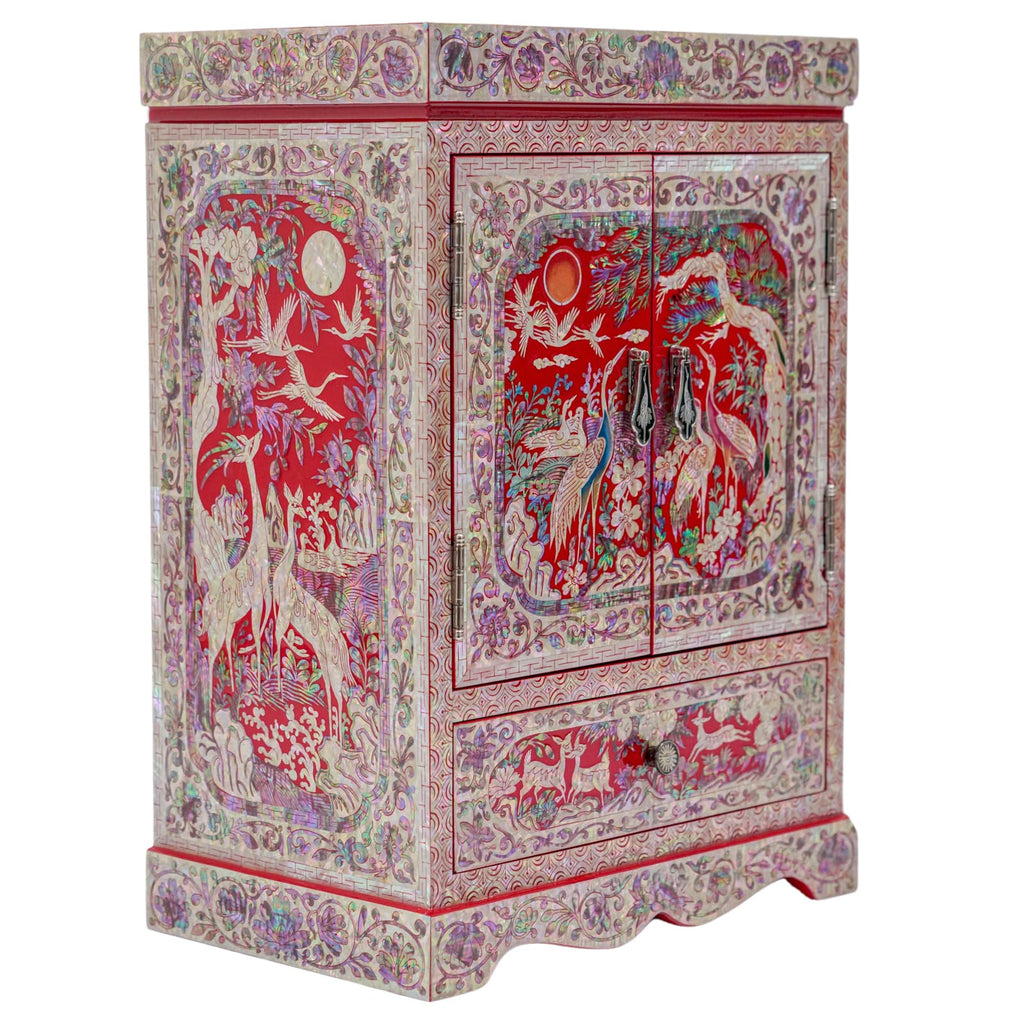 A red mother-of-pearl cabinet with moon and sun motifs, cranes, and lush floral patterns within an elaborate border on a scalloped base.