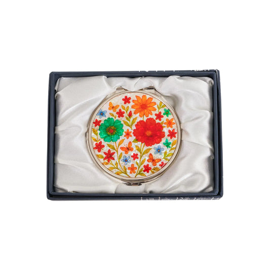 A round compact mirror with colorful floral design in a satin-lined box