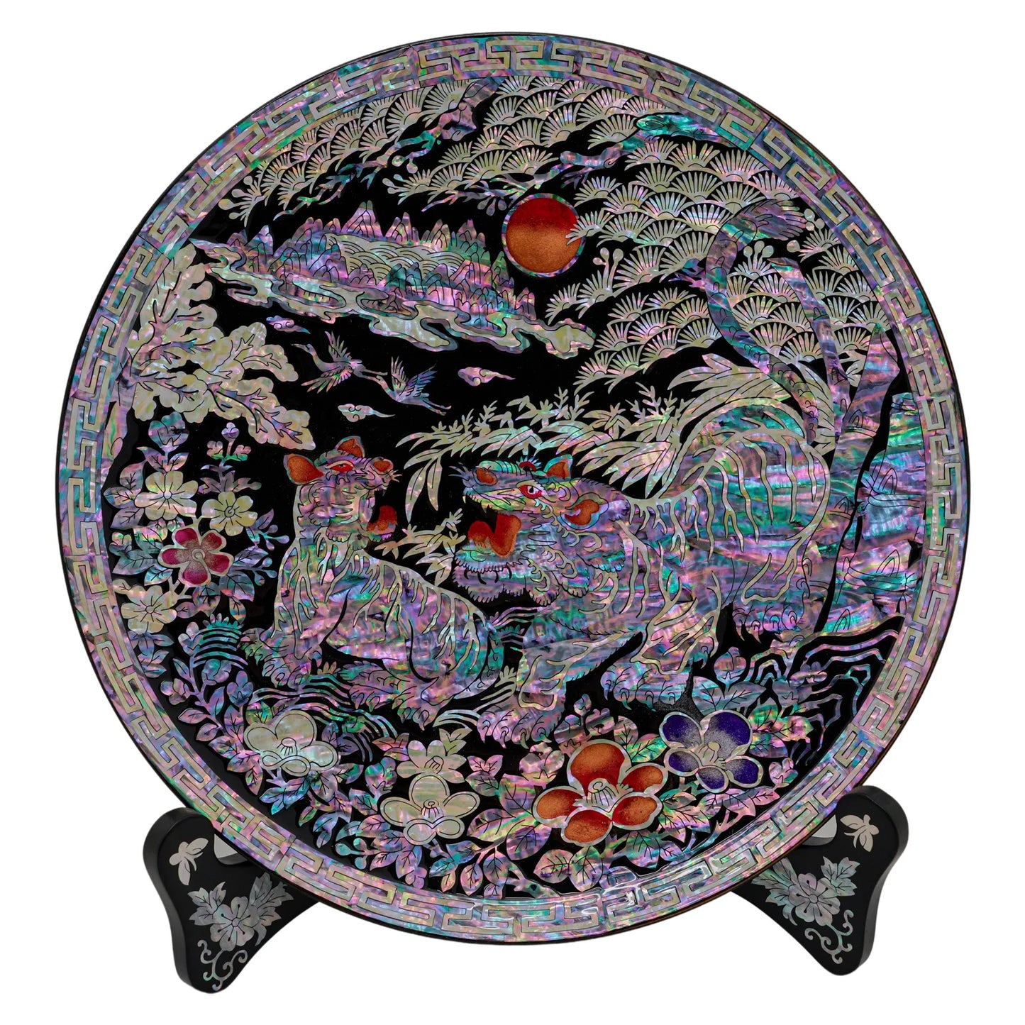 A round mother-of-pearl tray adorned with vibrant imagery of tigers amidst foliage under a moon, presented with intricate detail and color, supported by a decorative stand