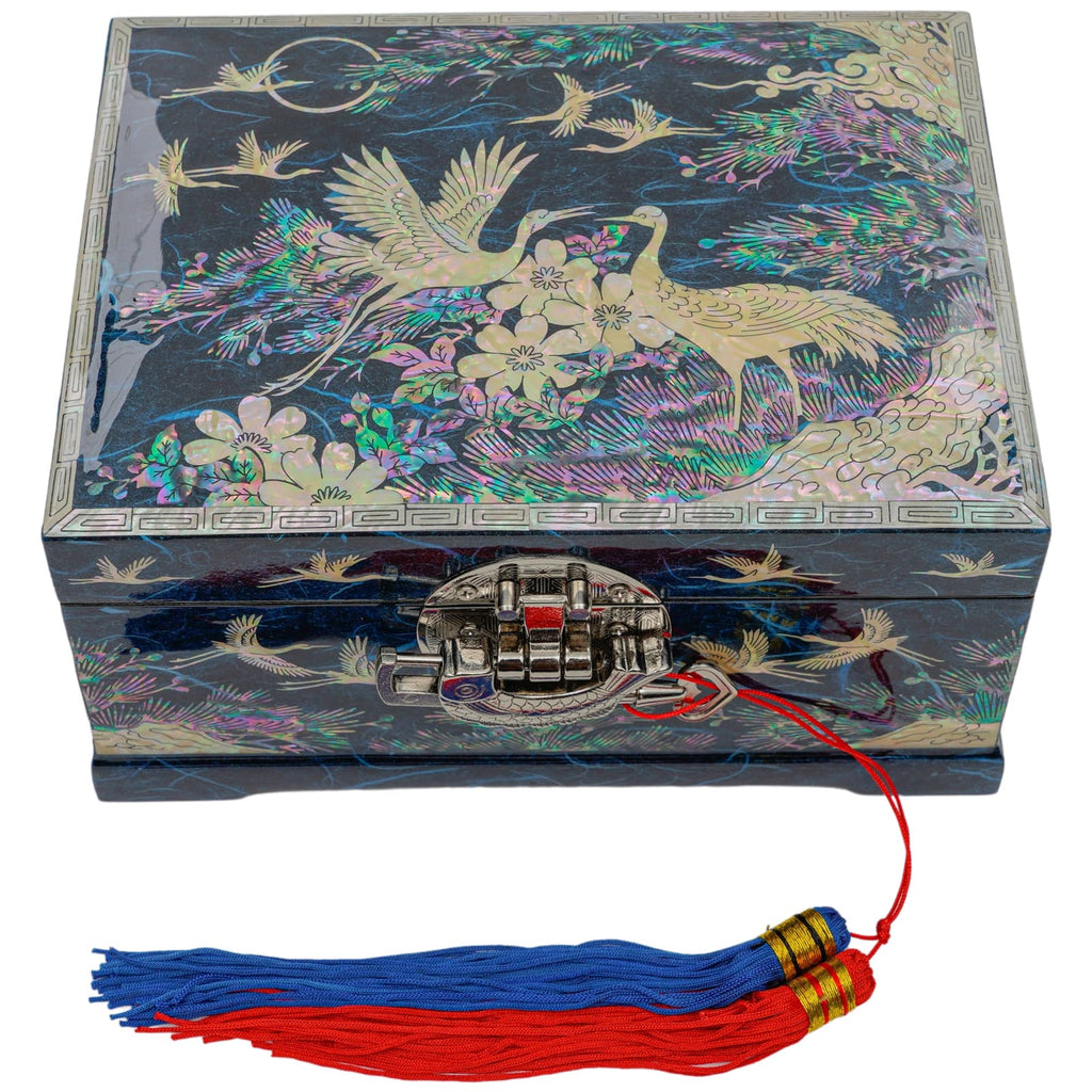 A square mother-of-pearl inlaid box with a detailed design of cranes and flowers on a dark background, featuring a metallic latch and a red string with a blue and red tassel attached.