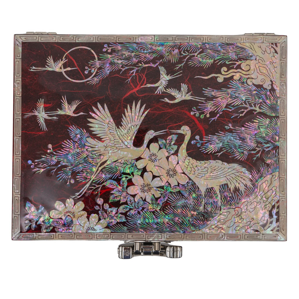 A traditional Mother of Pearl box with a detailed crane and floral pattern, featuring a geometric border and a silver clasp, set against a neutral background.