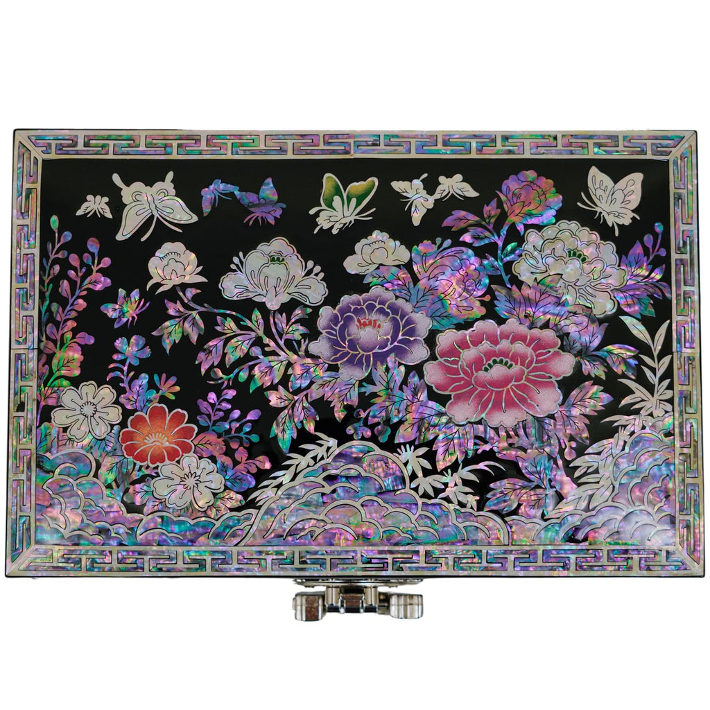 A mother-of-pearl jewelry box lid, displaying a vivid floral and butterfly painting, with intricate border patterns and front-facing clasps.
