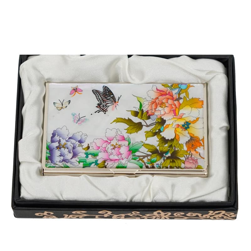 A vibrant floral card holder with images of colorful flowers and butterflies, presented in a black box with a white satin interior