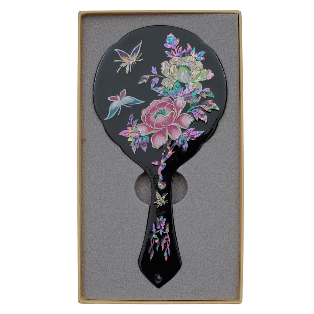 Black hand mirror with mother-of-pearl inlay of flowers and butterflies, displayed in a foam-lined box.