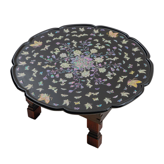 Black round table with scalloped edges, featuring intricate mother-of-pearl inlay of flowers and butterflies.