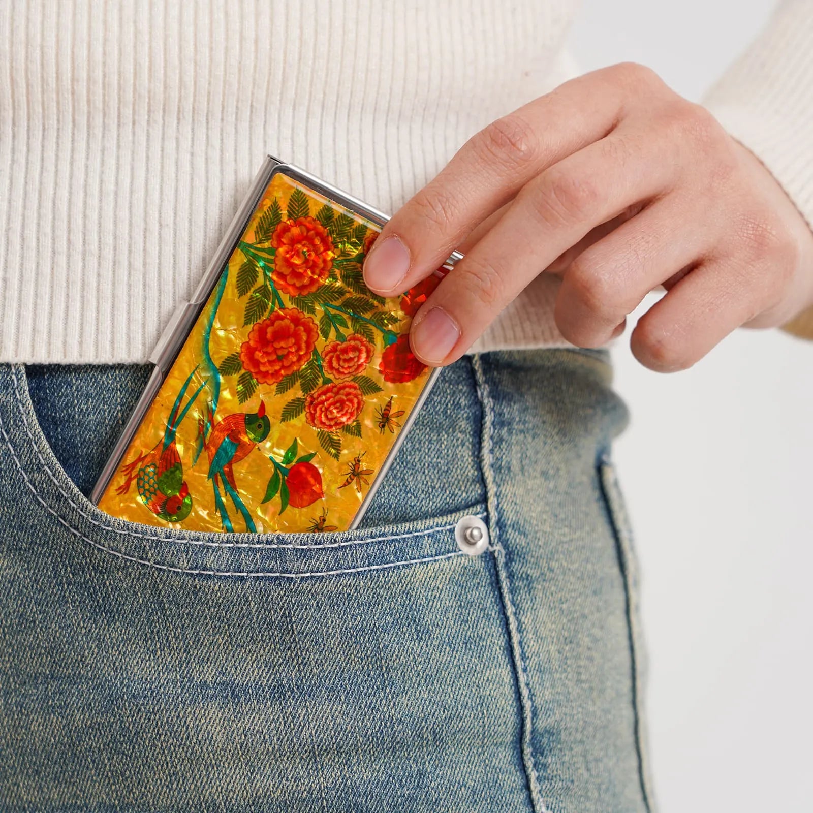 Card case with bird and flower design being placed into a jeans pocket