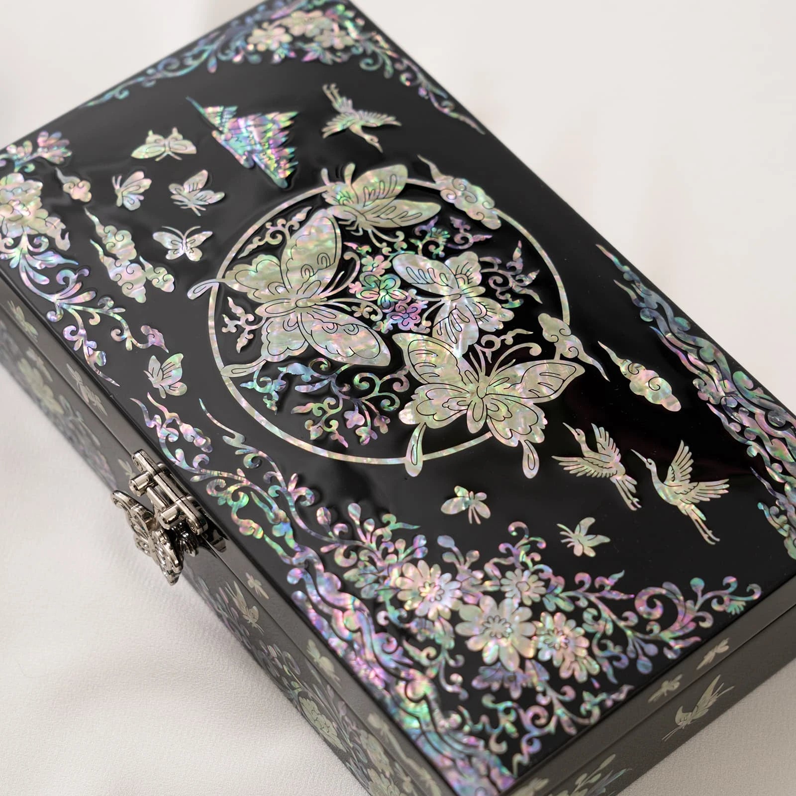 Close-up of a black lacquerware box featuring a striking circular nacre arrangement filled with detailed butterflies