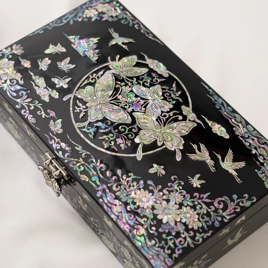 Close-up of a black lacquerware box featuring a striking circular nacre arrangement filled with detailed butterflies