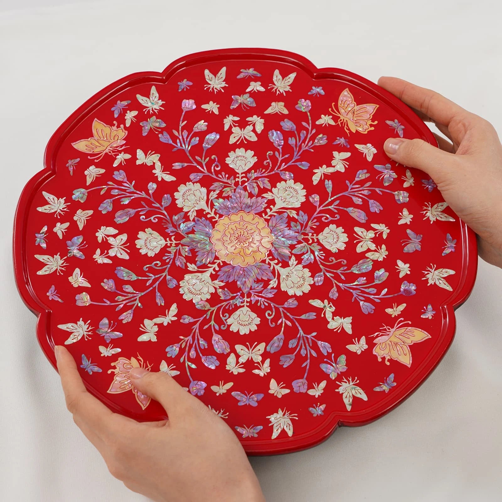 Close-up of red lacquer mother of pearl tray featuring intricate floral and butterfly design with iridescent shell inlay.