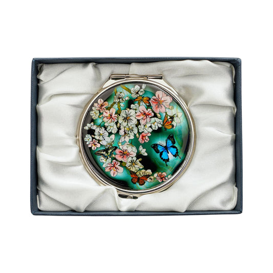Compact mirror with blooming flowers and vibrant butterflies on a green background, in a satin gift box