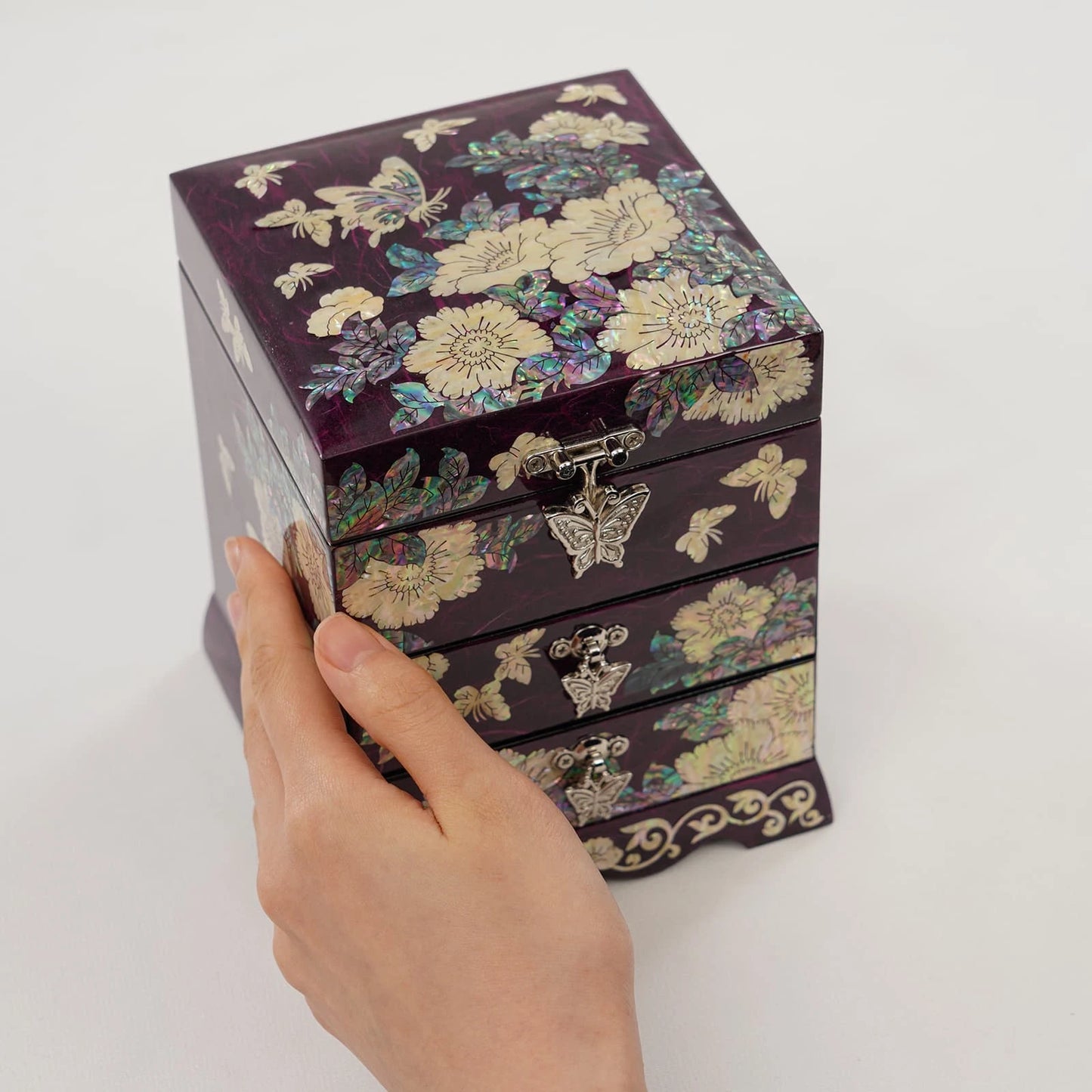 Deep purple jewelry box with shimmering mother of pearl floral design. Multi-level accessory storage with elegant butterfly shaped drawer pulls.