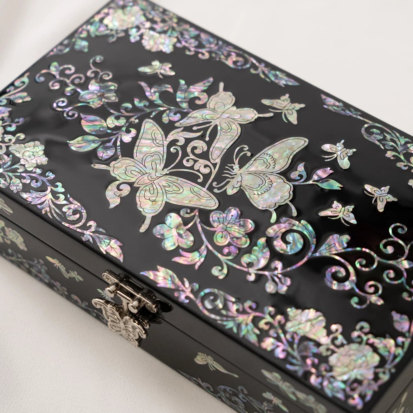 Detailed view of a black keepsake box with prominent iridescent butterfly and floral vine inlays, highlighting the fine craftsma