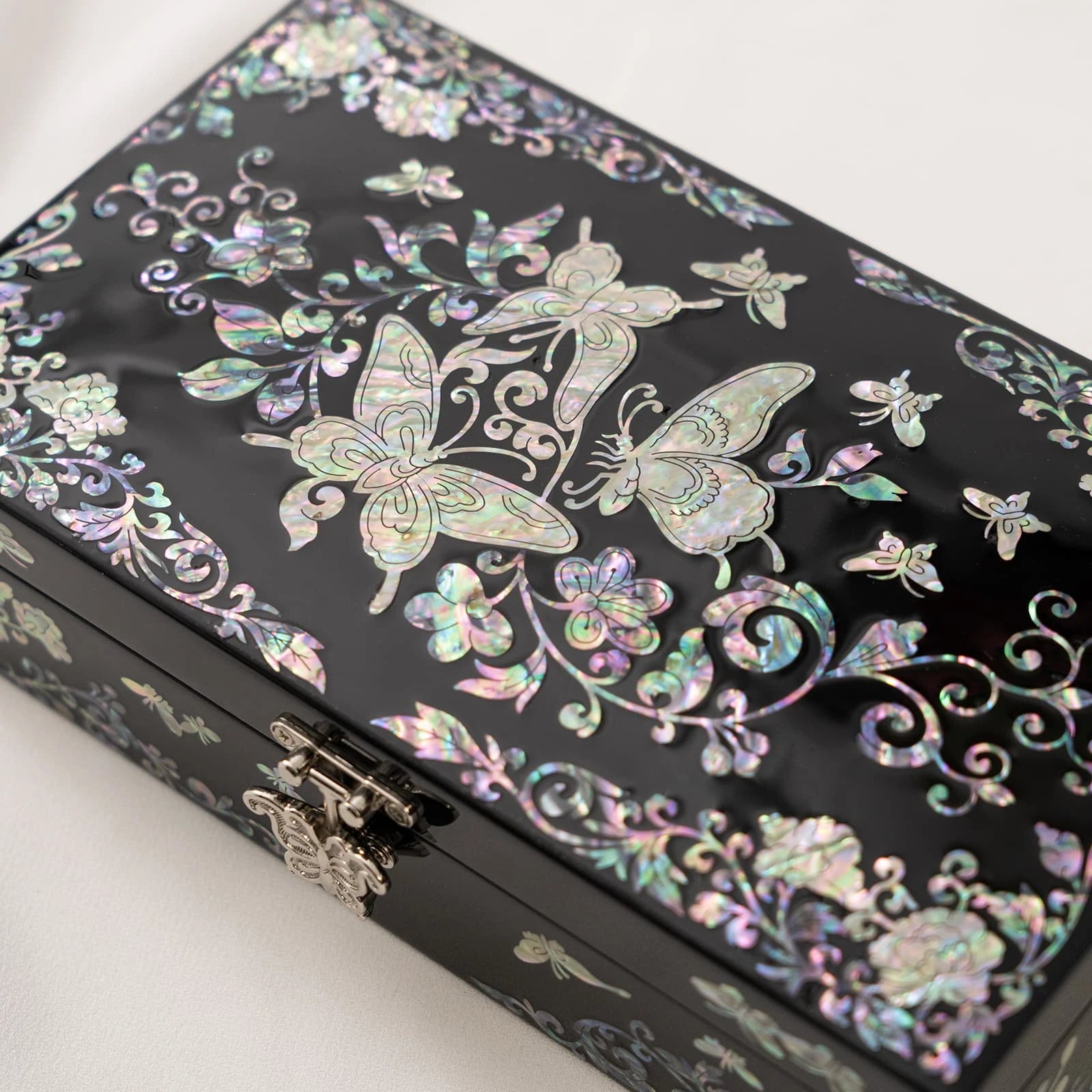 Detailed view of a black keepsake box with prominent iridescent butterfly and floral vine inlays, highlighting the fine craftsma