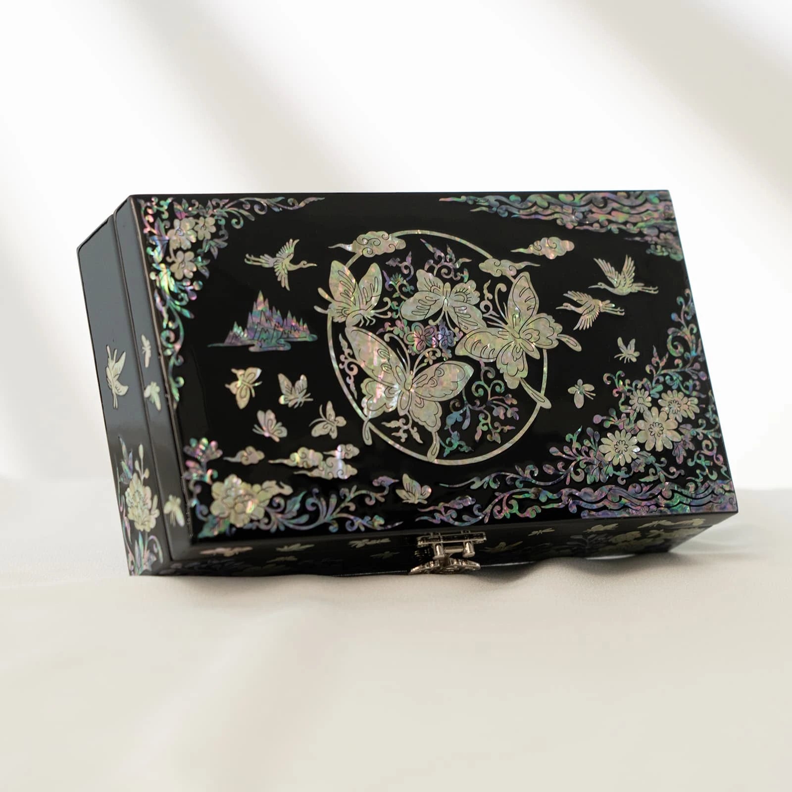 Elegant black jewelry box featuring a striking circular nacre layout with butterflies, mountains, and clouds under subtle lighting