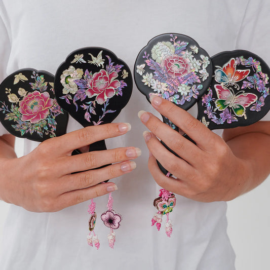 Four black mother-of-pearl hand mirrors, each held with unique tassels