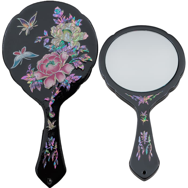 Front and back of a black hand mirror with mother-of-pearl inlay featuring butterflies and floral designs.