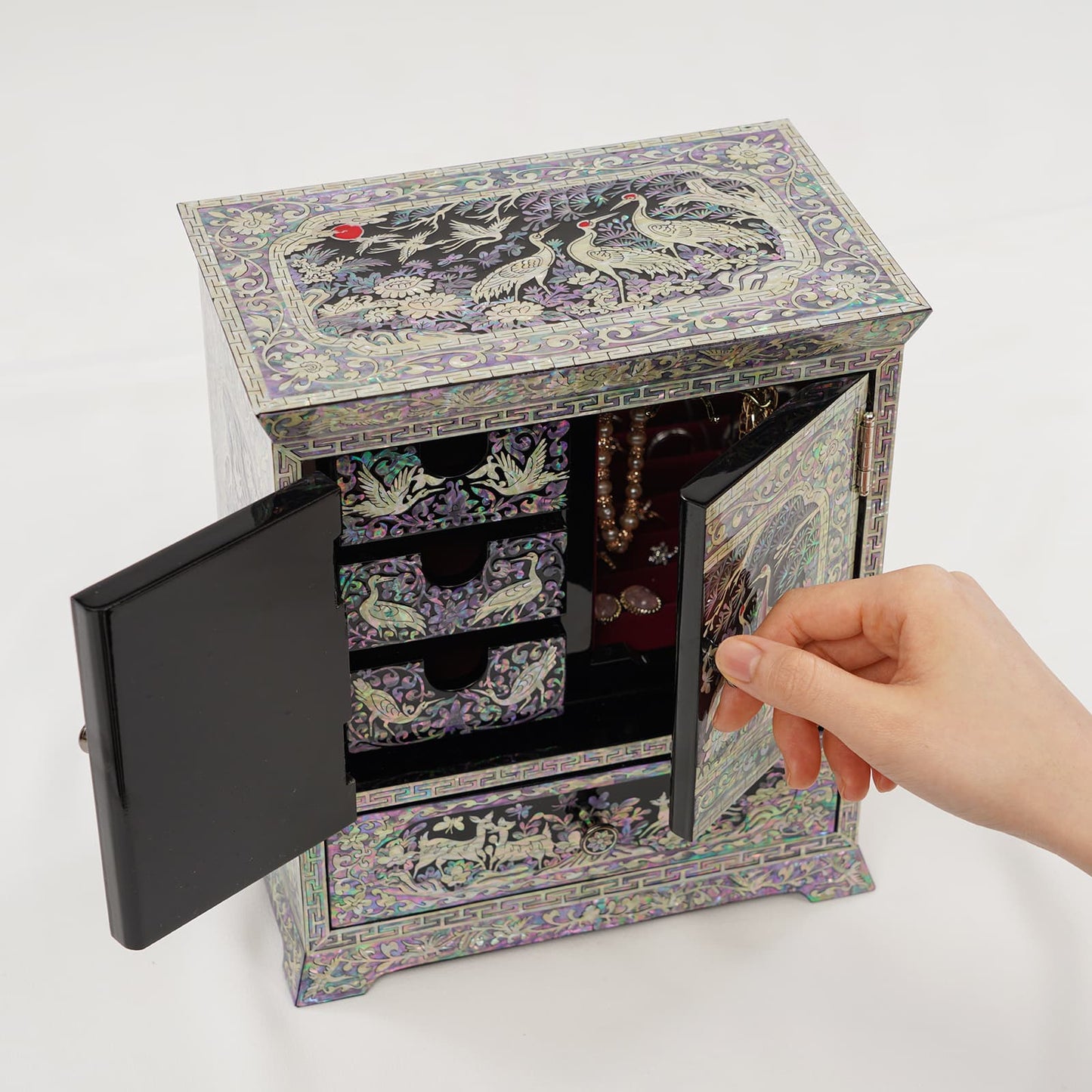 Handcrafted mother of pearl jewelry cabinet with double doors open, revealing drawers and necklace storage inside