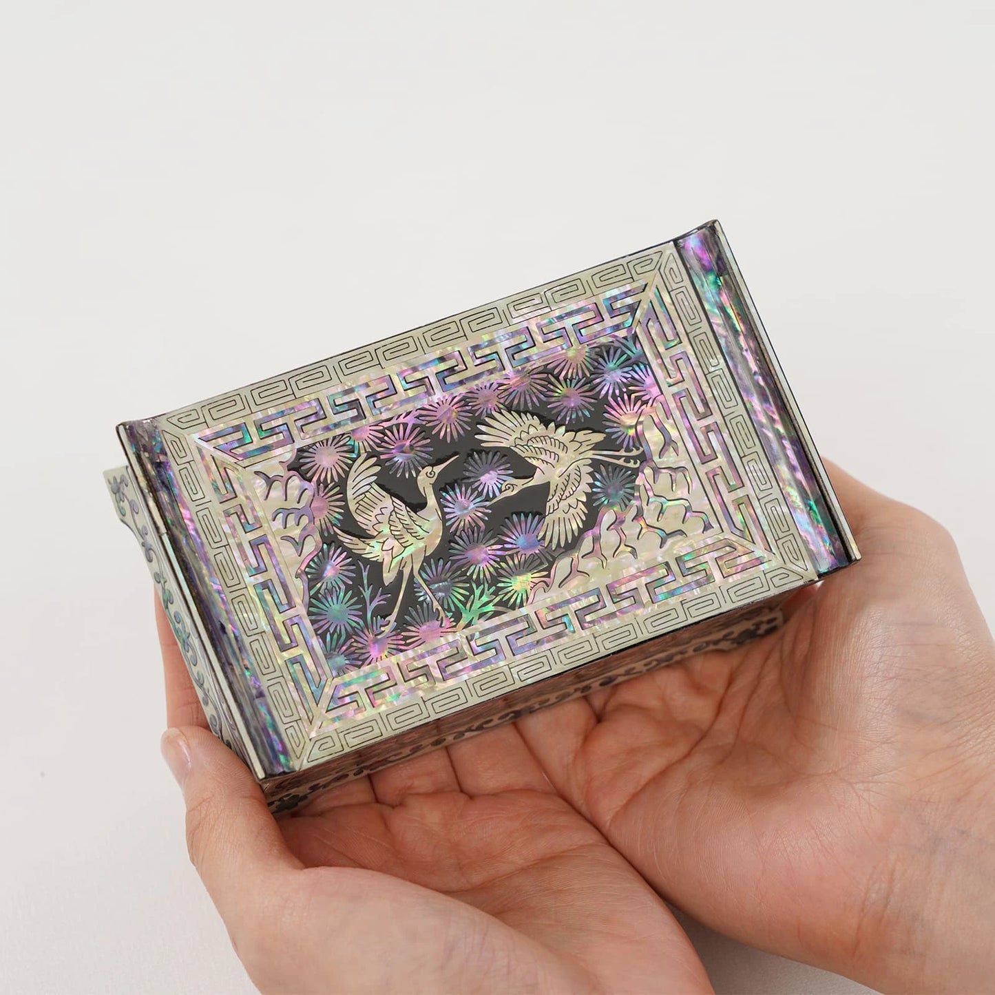 Handheld Korean jewelry box with a different crane and pine tree shell design. Vibrant iridescent colors on a small handmade gift