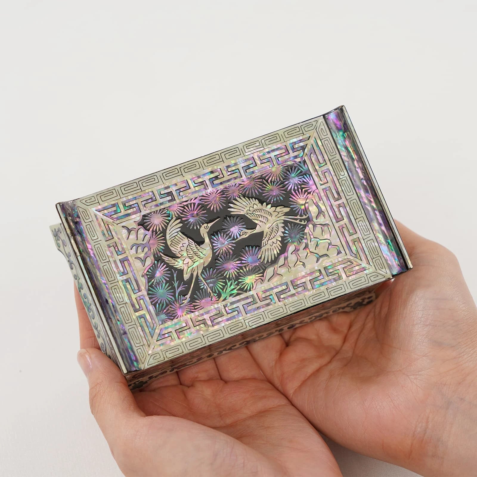 Handheld Korean jewelry box with a different crane and pine tree shell design. Vibrant iridescent colors on a small handmade gift
