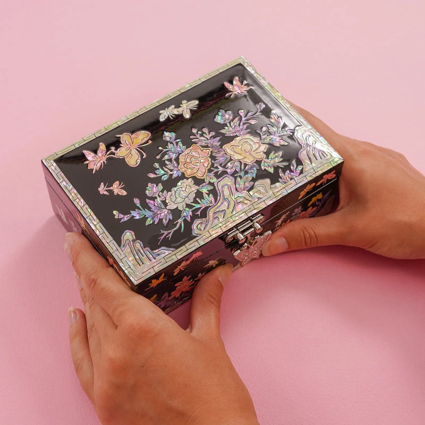 Hands holding a glossy black box with peony and butterfly mother-of-pearl inlay