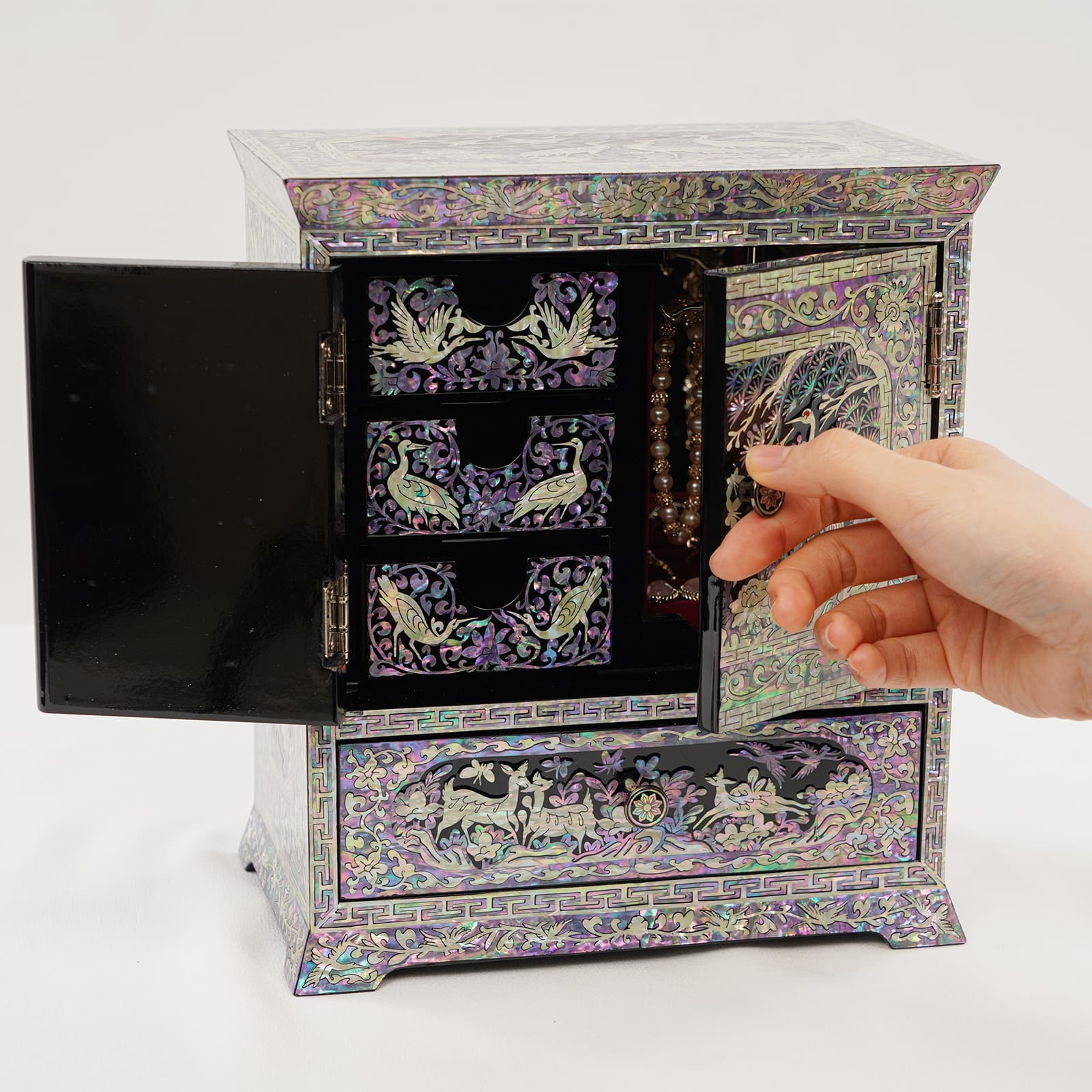 Korean mother of pearl jewelry box cabinet with doors partially open, showing interior compartments and iridescent crane design
