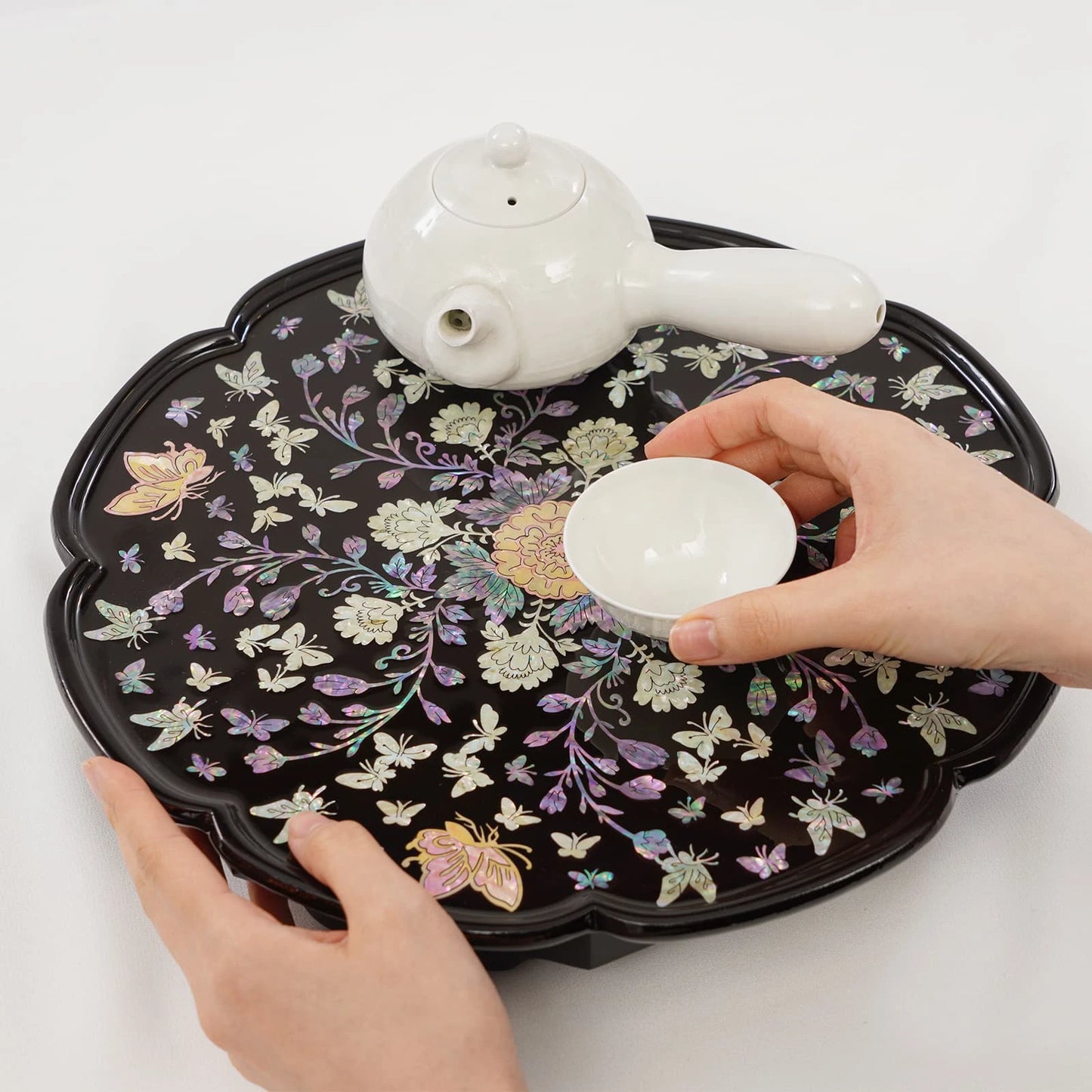 Mother of pearl tea serving tray holding white ceramic teapot and teacup, showcasing traditional Korean lacquer craftsmanship.