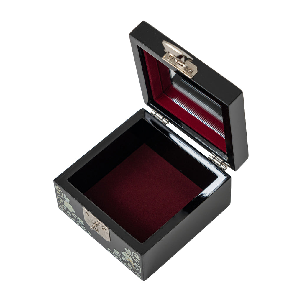 Open_black_mother-of-pearl_jewelry_box_with_a_deep_red_velvet_interior_and_a_silver_latch