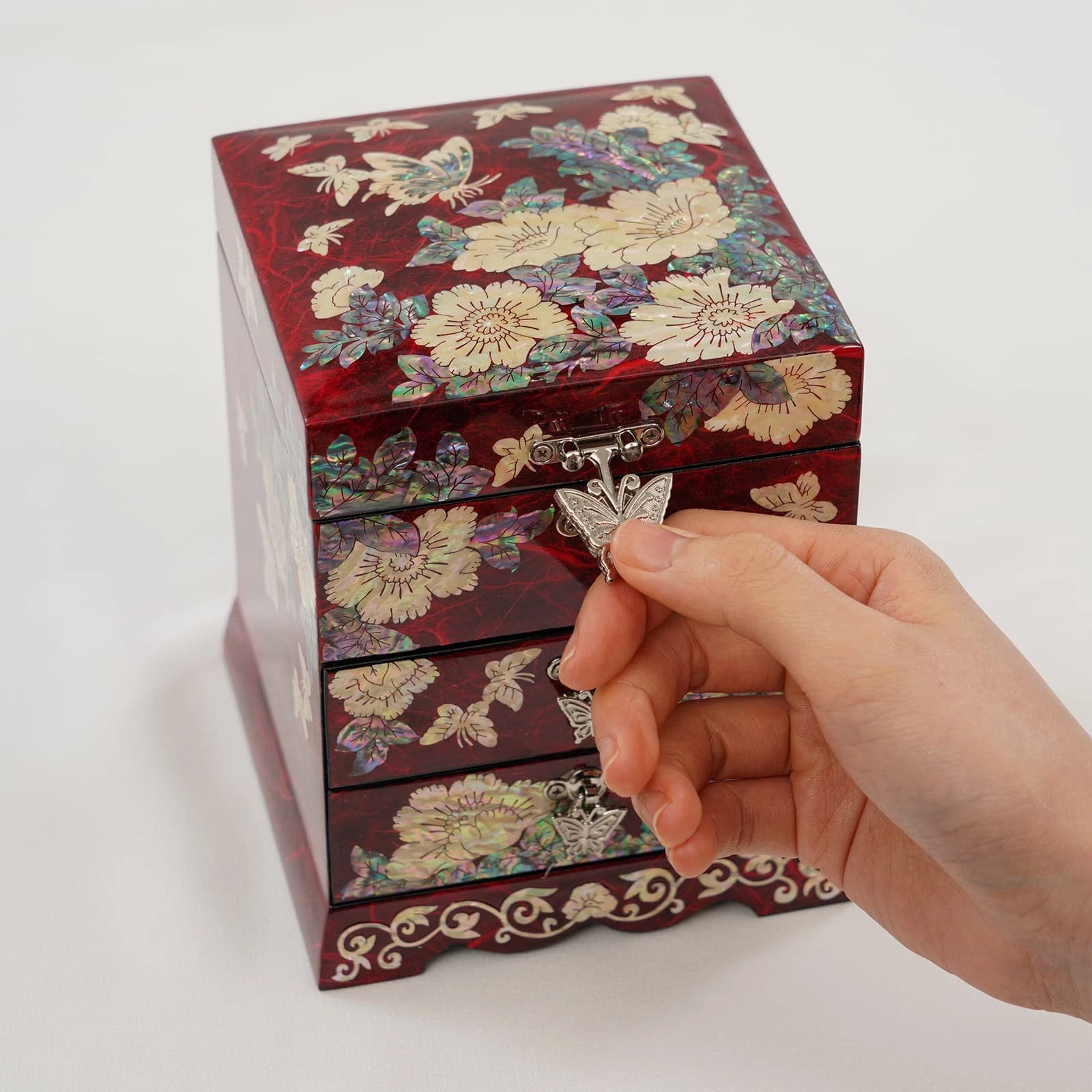 Opening a luxurious red trinket box with radiant mother of pearl inlay. High-gloss handcrafted wood organizer for fine jewelry and heirlooms.
