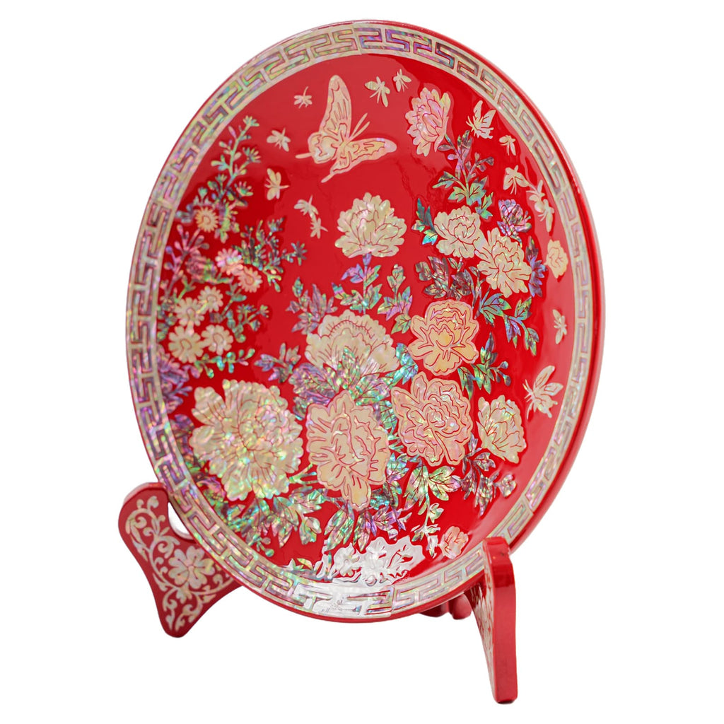 Red decorative plate with mother-of-pearl inlay, featuring floral designs and butterflies on a stand.