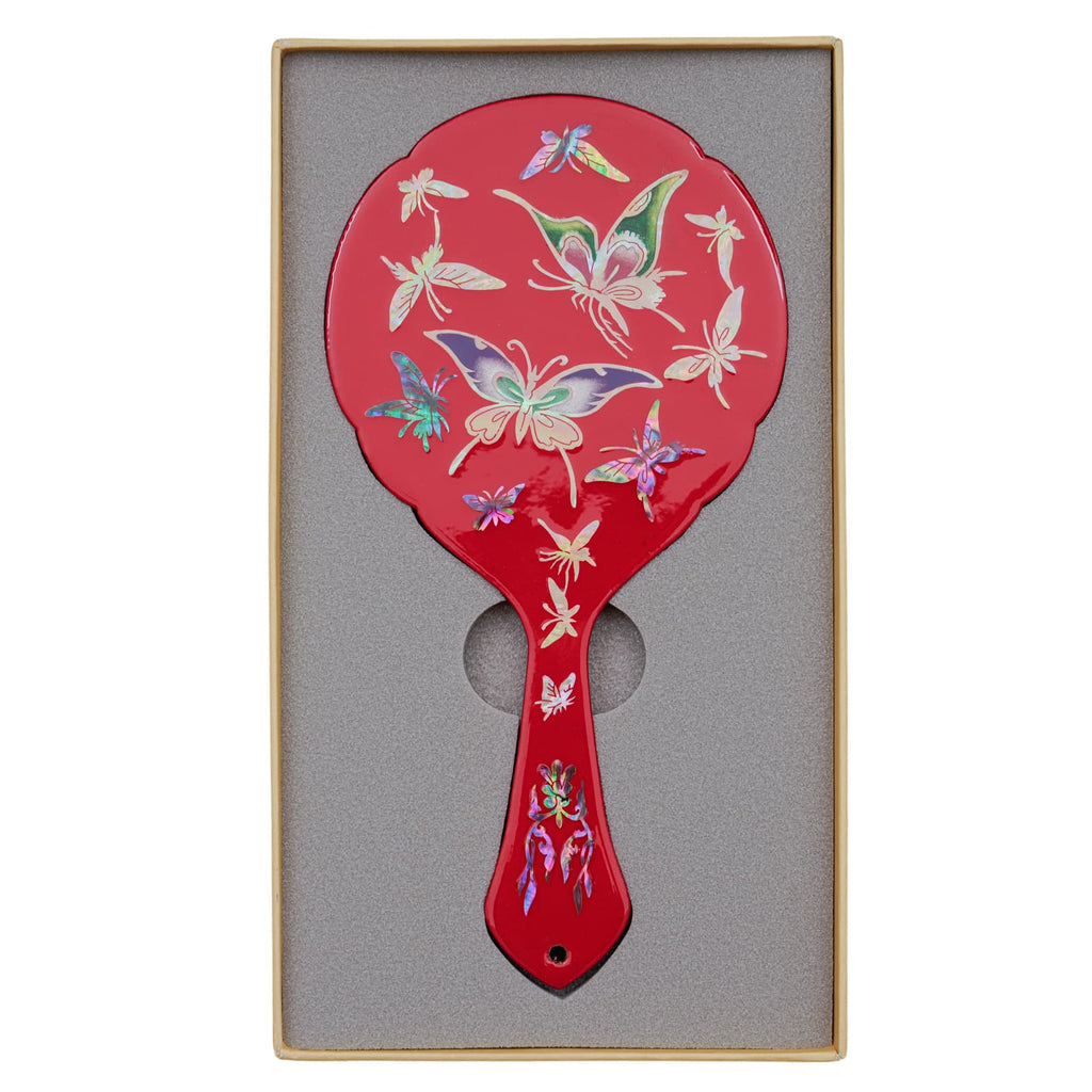 Red hand mirror with a mother-of-pearl butterfly design, displayed in a foam-lined box for safe storage.