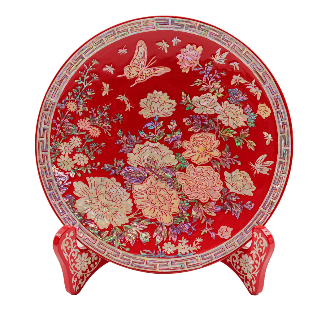 Round red lacquered plate with intricate mother-of-pearl inlay of flowers and butterflies, displayed on a matching decorative stand.