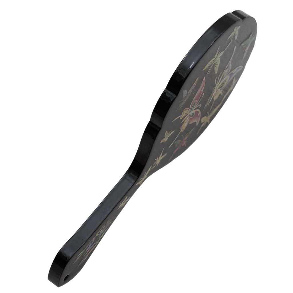 Side view of a black hand mirror with mother-of-pearl butterfly inlay, highlighting its slim design.