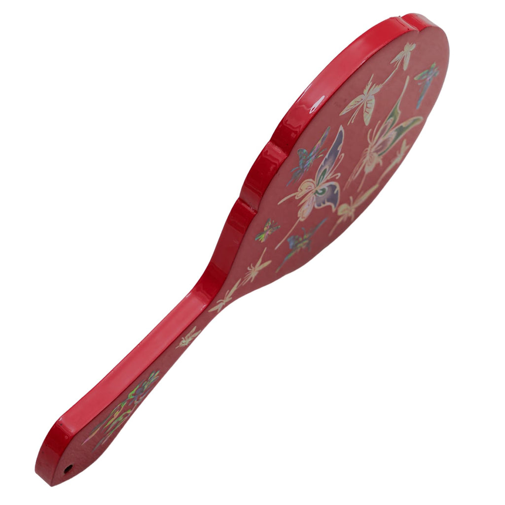 Side view of a red hand mirror with mother-of-pearl butterfly inlay, highlighting its slim design.