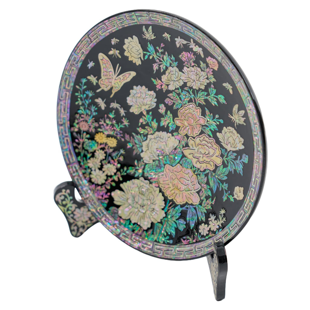 Side view of a round black lacquered plate with intricate mother-of-pearl inlay of flowers and butterflies, displayed on a decorative stand.