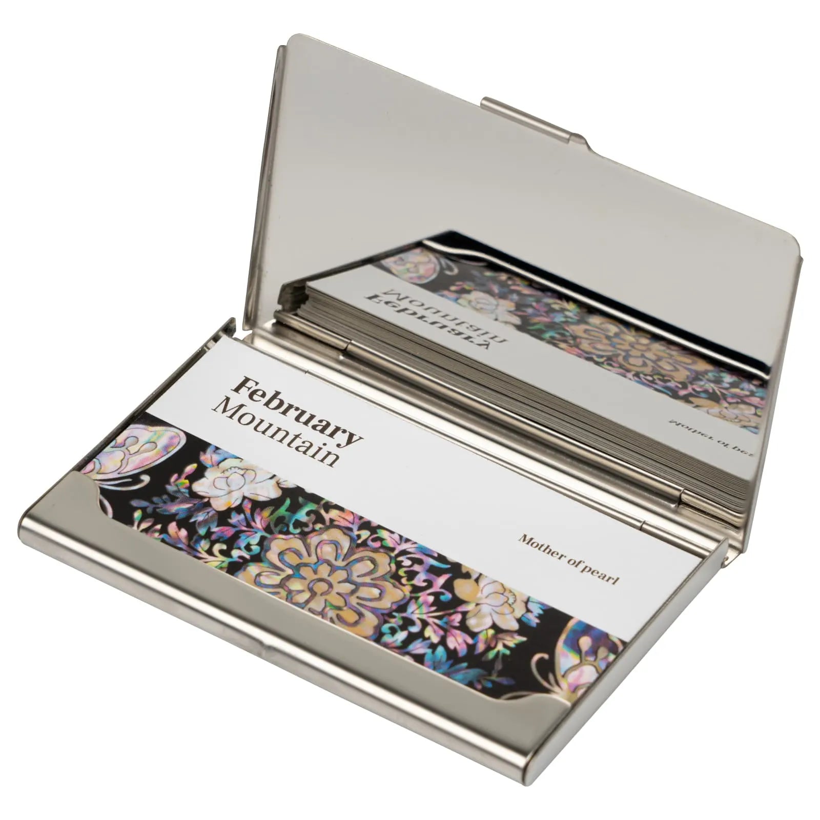 Silver business card holder with floral designs on a white background