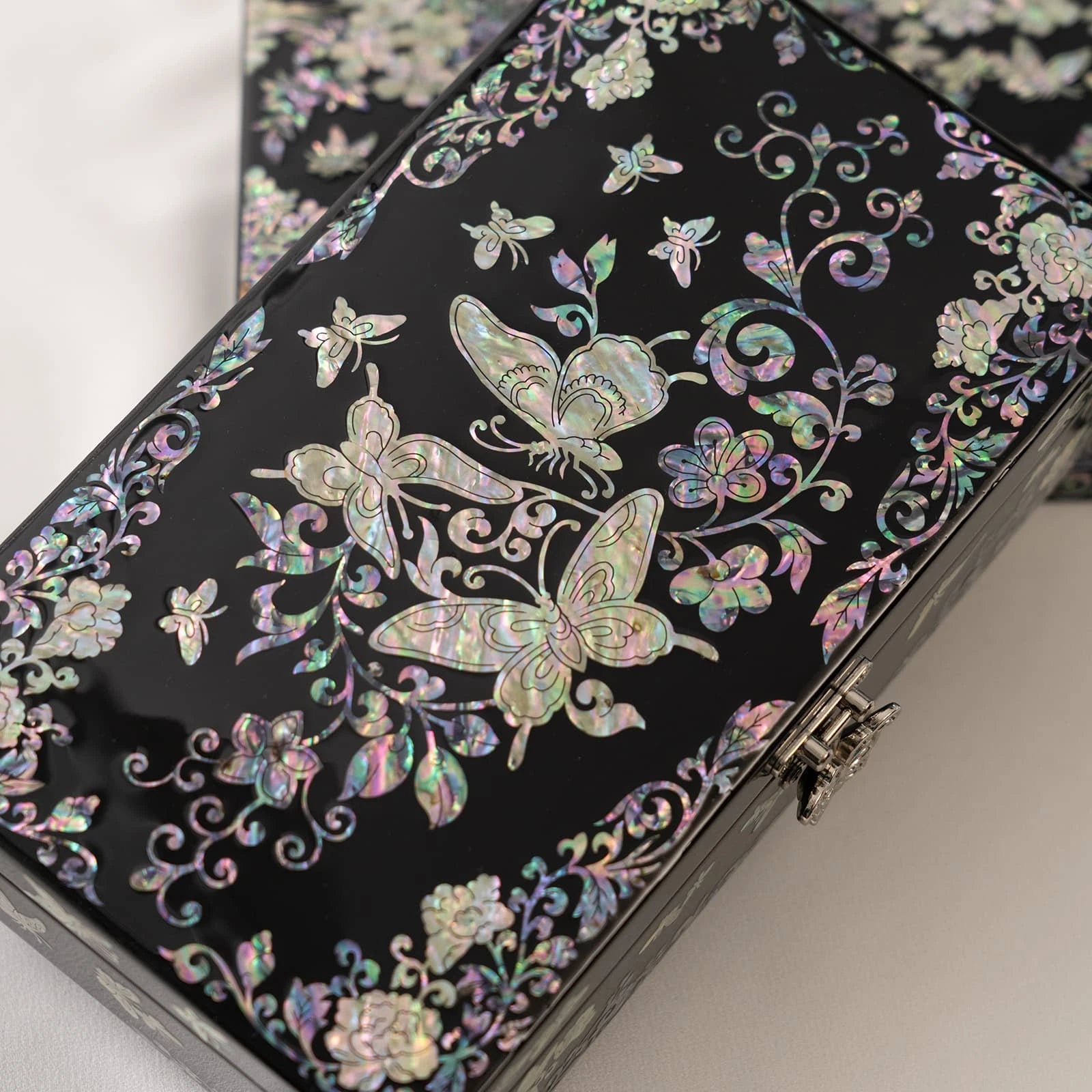Sophisticated black jewelry box adorned with intricate, symmetrical iridescent butterfly and floral vine inlays
