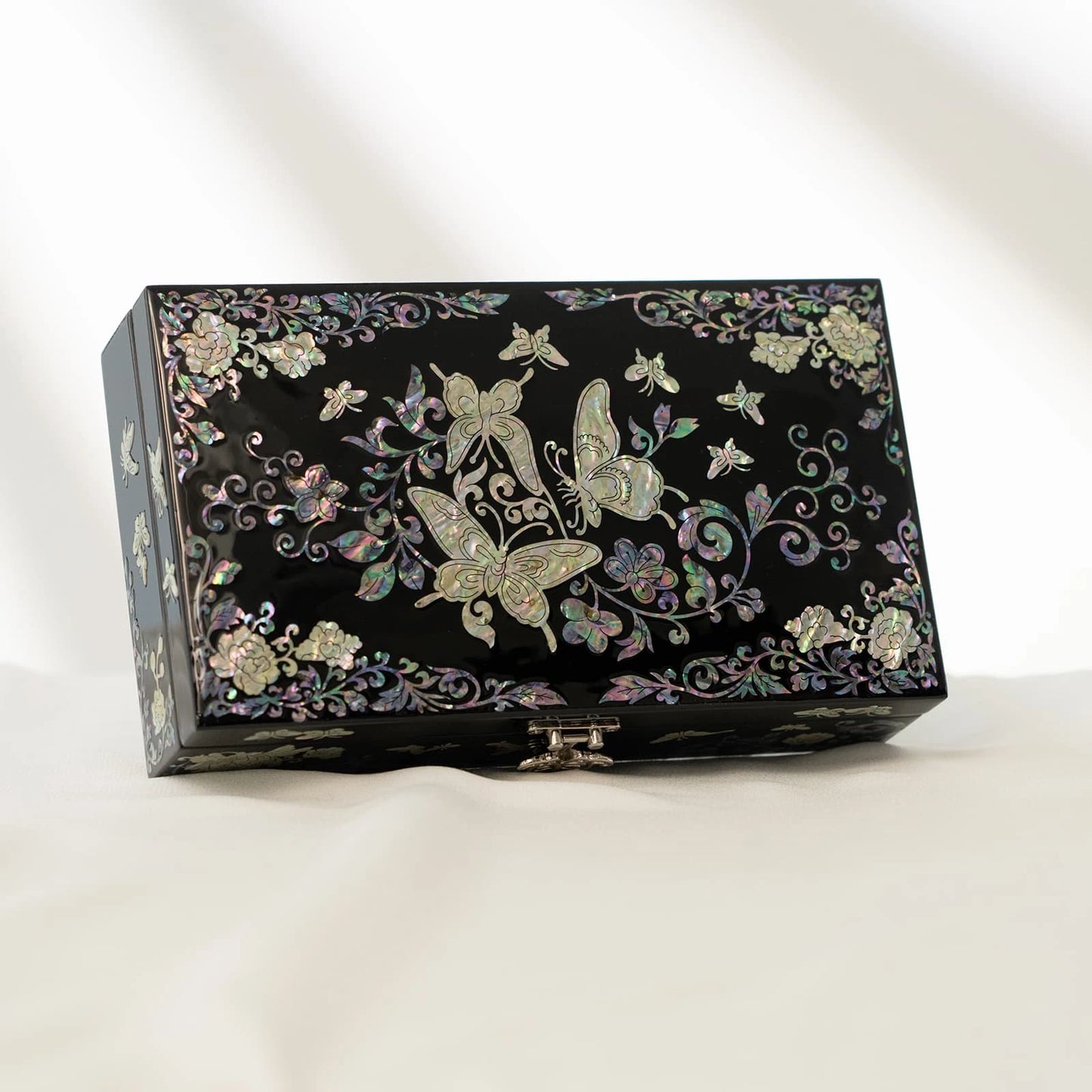Sophisticated black keepsake box with a symmetrical mother-of-pearl butterfly and floral border design, equipped with a metal la