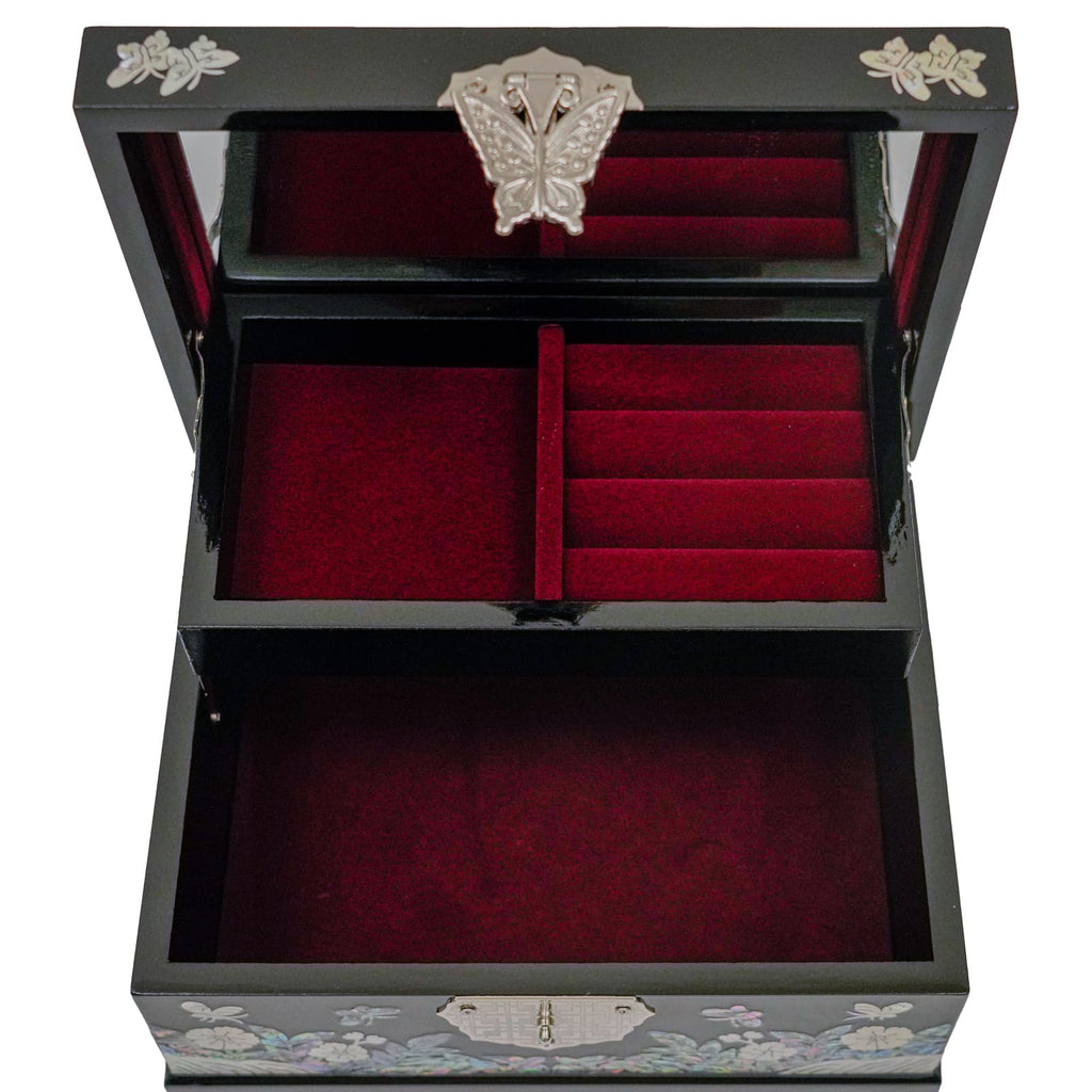 An open jewelry box with red velvet lining and multiple compartments. The box is black with a floral design and a metal butterfly on the lid.