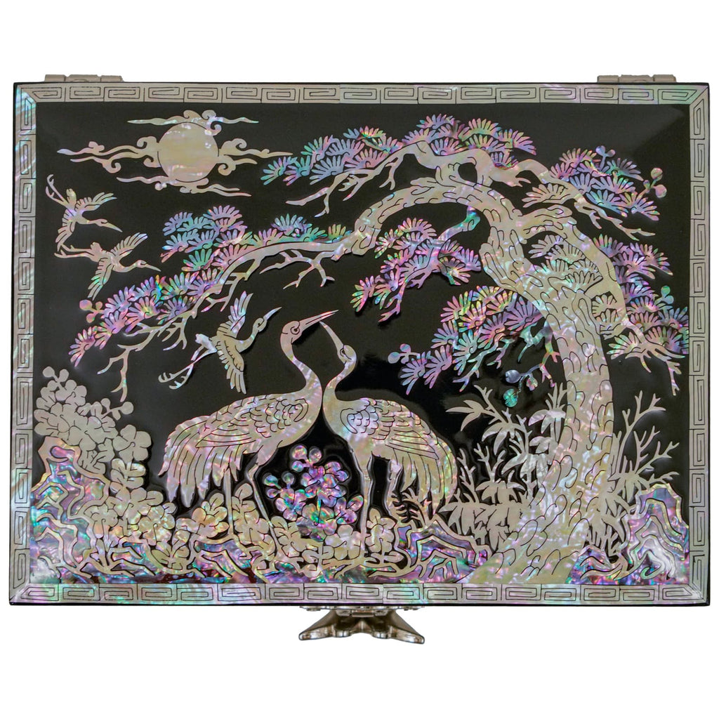 This image shows a Mother of Pearl jewelry box with an intricate design of two cranes under a pine tree, displayed with a stand for an elevated view.