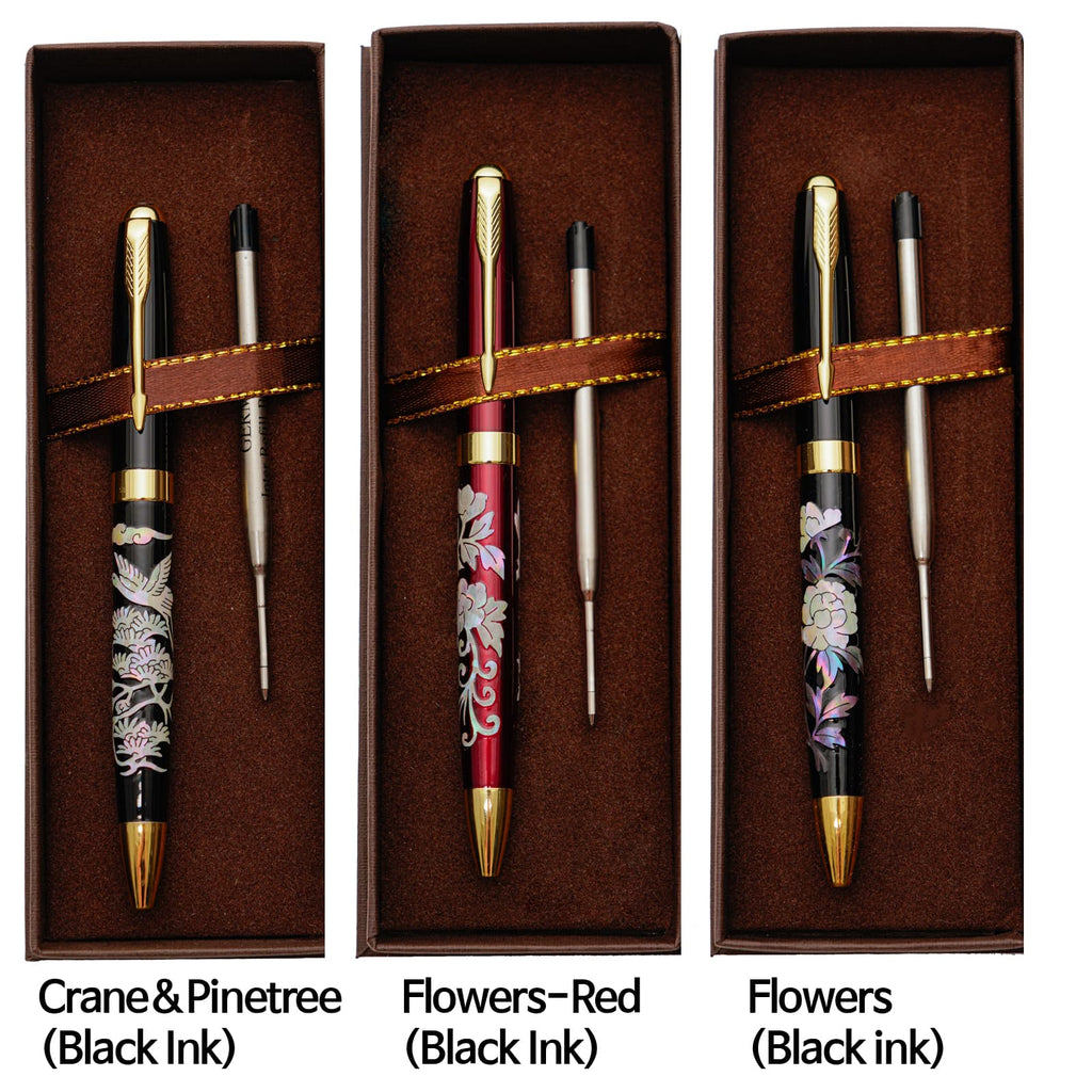 Three ballpoint pens with mother-of-pearl inlay designs (crane and pine tree, red flowers, flowers) lie in brown boxes with refills, labeled with their patterns and ink type.