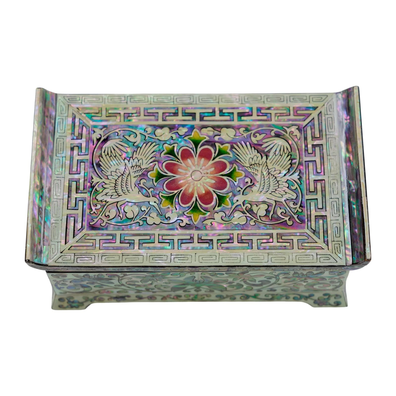 Top-down view of a mother of pearl jewelry box. Symmetrical crane and floral shell inlay with a traditional geometric border