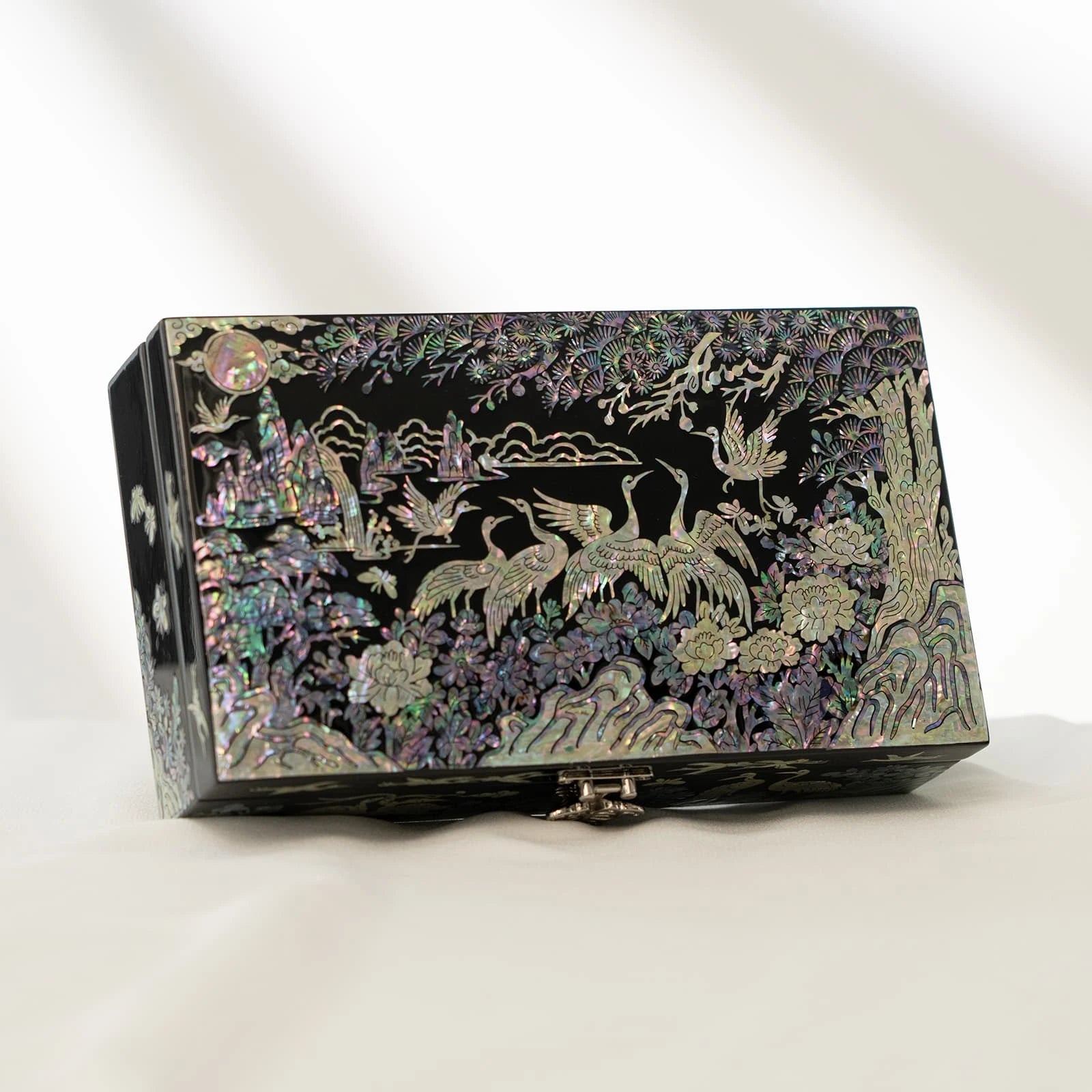 Traditional black lacquer box showcasing a complete iridescent landscape scene of cranes, a glowing moon, and pine trees