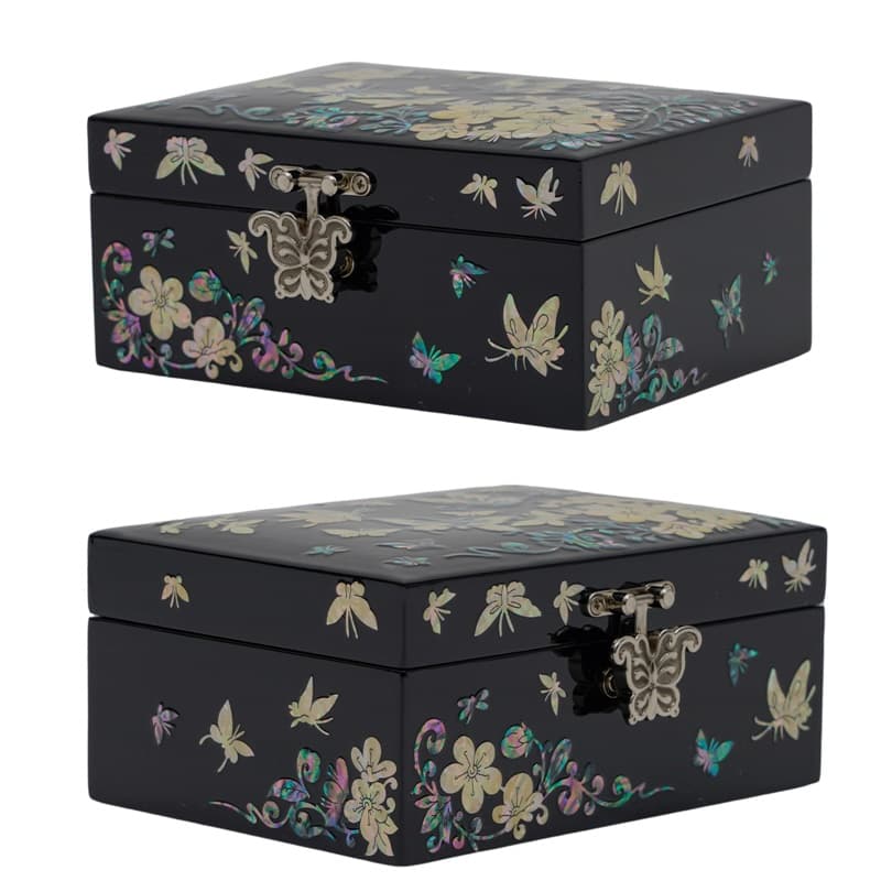Two closed black lacquer boxes with intricate mother-of-pearl butterfly and floral inlays and decorative metal clasps, crafted in a traditional Asian style.