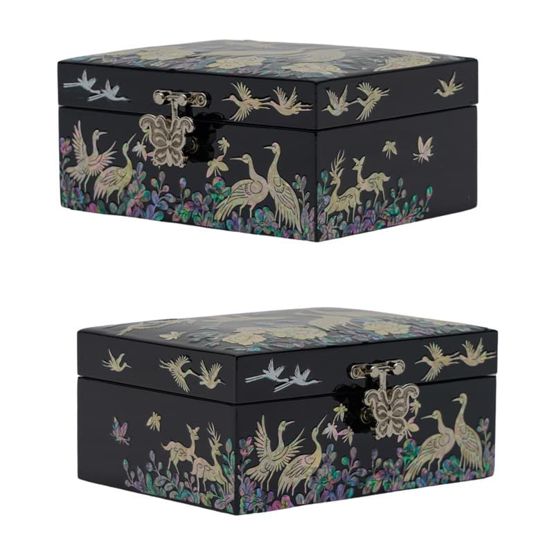 Two closed black lacquer boxes with intricate mother-of-pearl inlays depicting cranes and florals, displaying traditional Asian artistry.